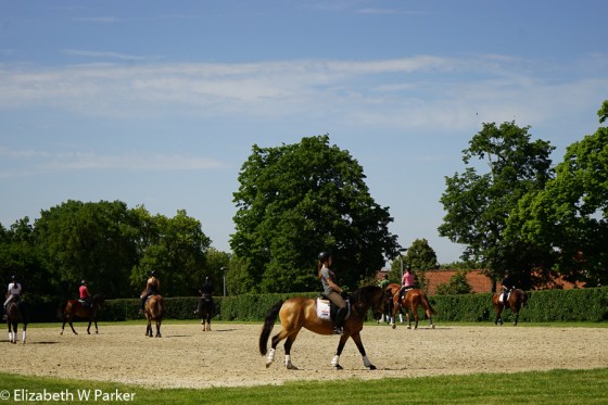 Riders practicing for the Olympic trial judging going on elsewhere at the stables.